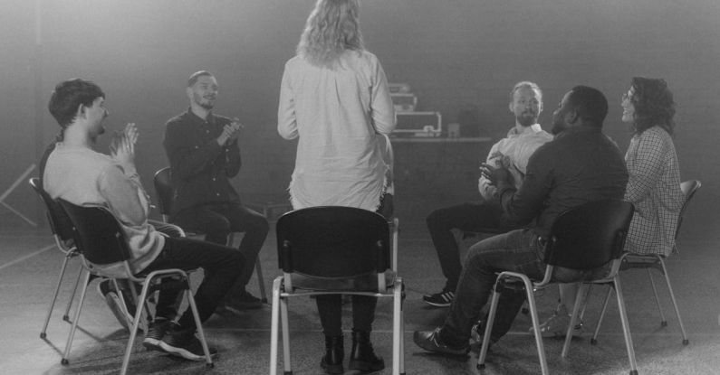 Group Therapy - Woman Standing Beside a Group of People Sitting on Chairs