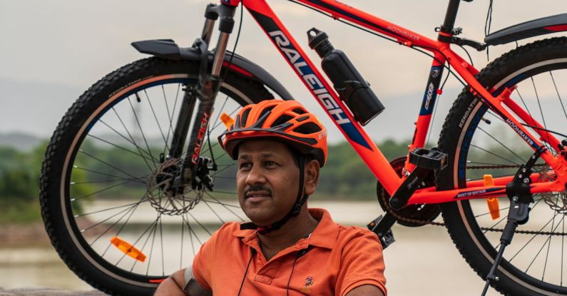 Routine - Photo of Man Wearing Orange Polo Shirt Sitting Beside His Bike